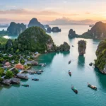 Scenic view of Thailand featuring limestone islands, a traditional long-tail boat, lush tropical scenery, and a golden Buddhist temple at sunrise.