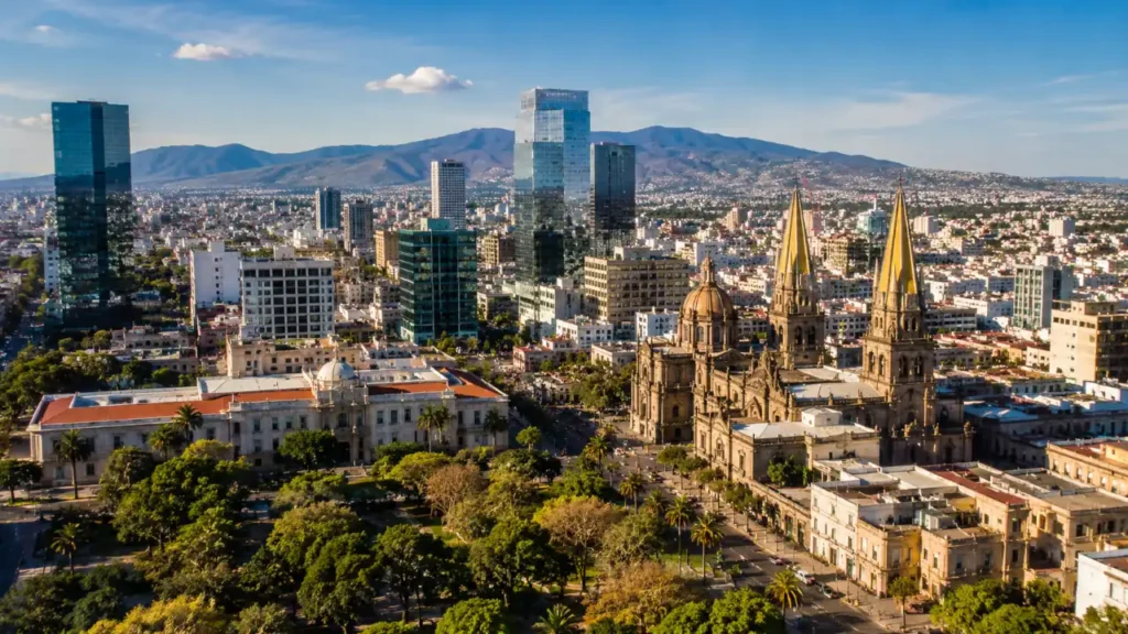 Panoramic view of Guadalajara's skyline showing modern skyscrapers alongside historic architecture with mountains in the background.