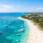Aerial view of Playa del Carmen's turquoise Caribbean coastline with white sandy beaches, boats, palm trees, and sunshine.