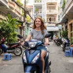 Woman smiling on a scooter in a residential neighborhood in Ho Chi Minh City